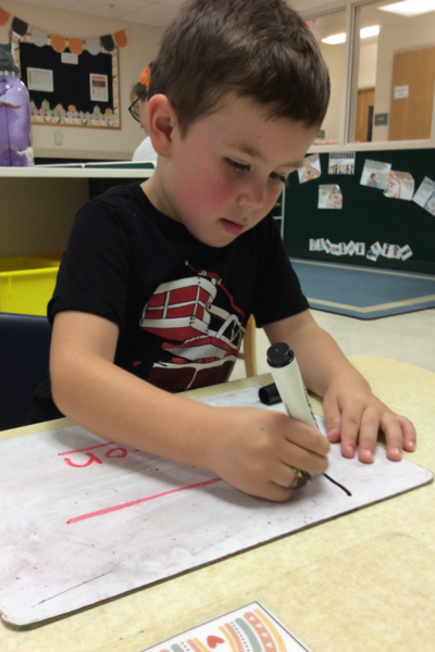 Kolton sitting at a desk writing on paper using a pen.