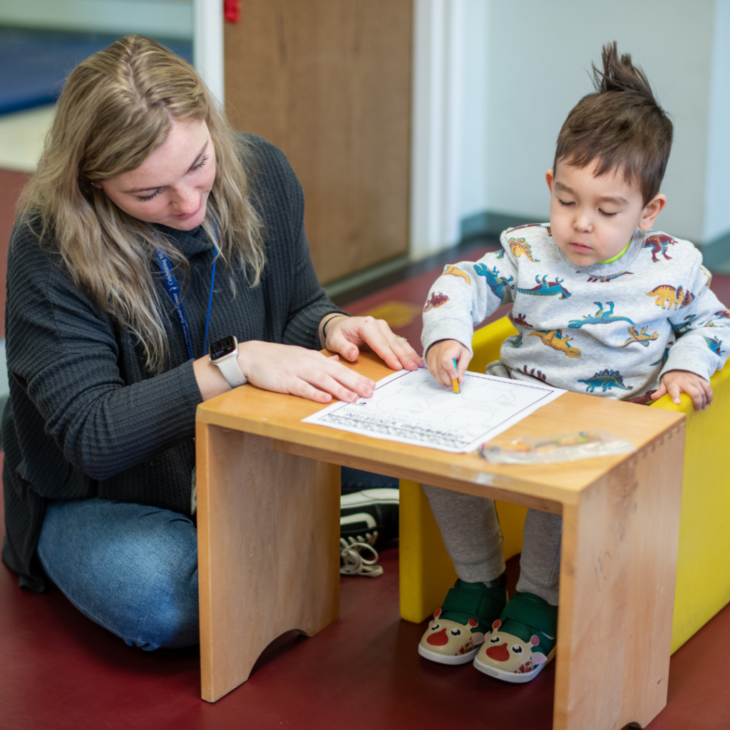 Woman helping child practice writing.