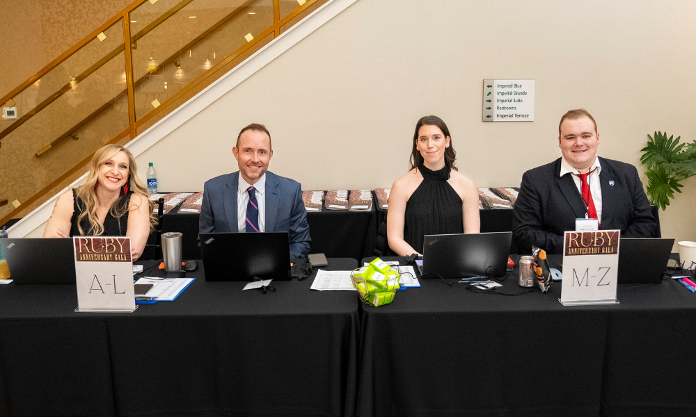 Four volunteers at the check in table of the gala smiling.