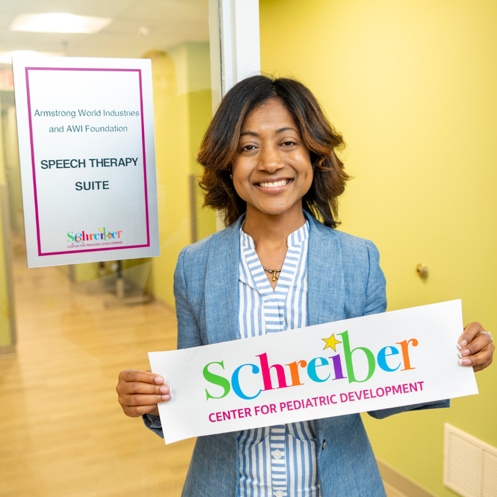 woman holding up Schreiber logo banner in front of yellow hallway