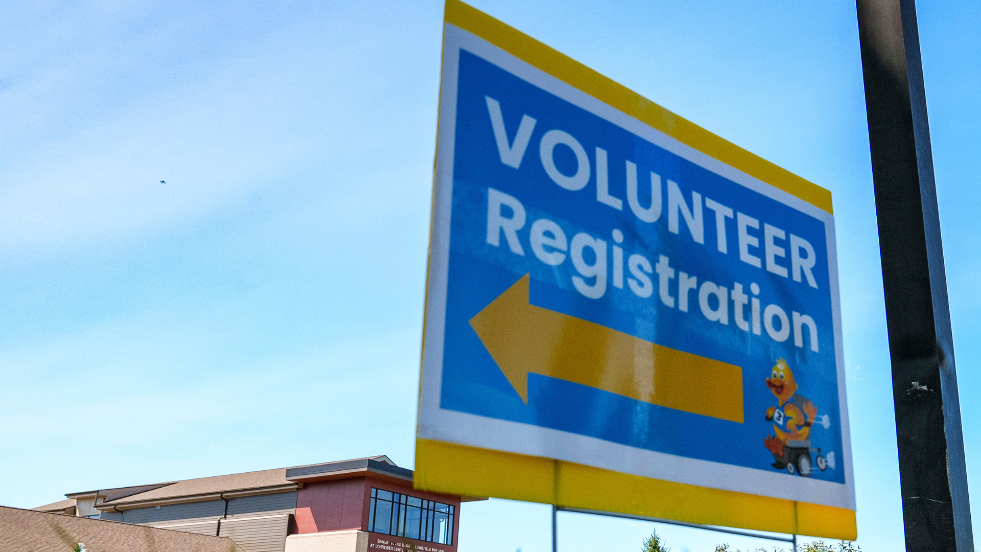 blue and yellow sign that reads volunteer registration with big yellow arrow